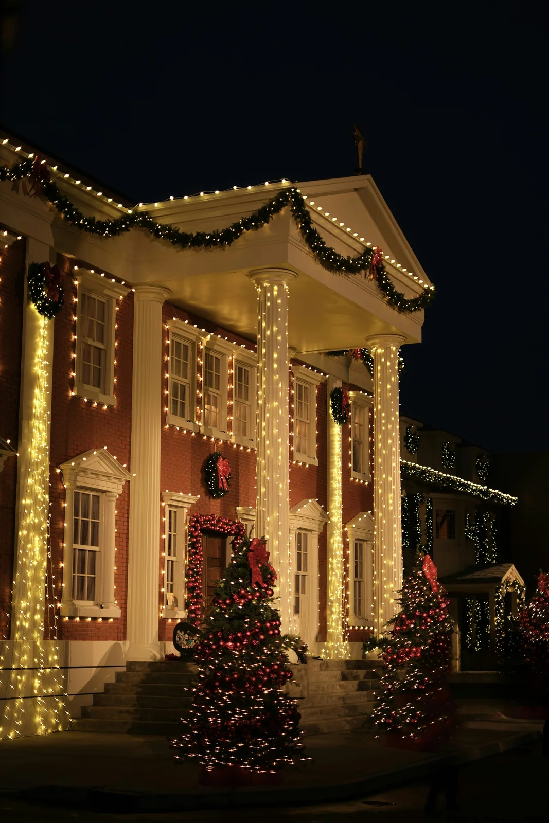 Illustrative residential exterior decorated with warm holiday lights