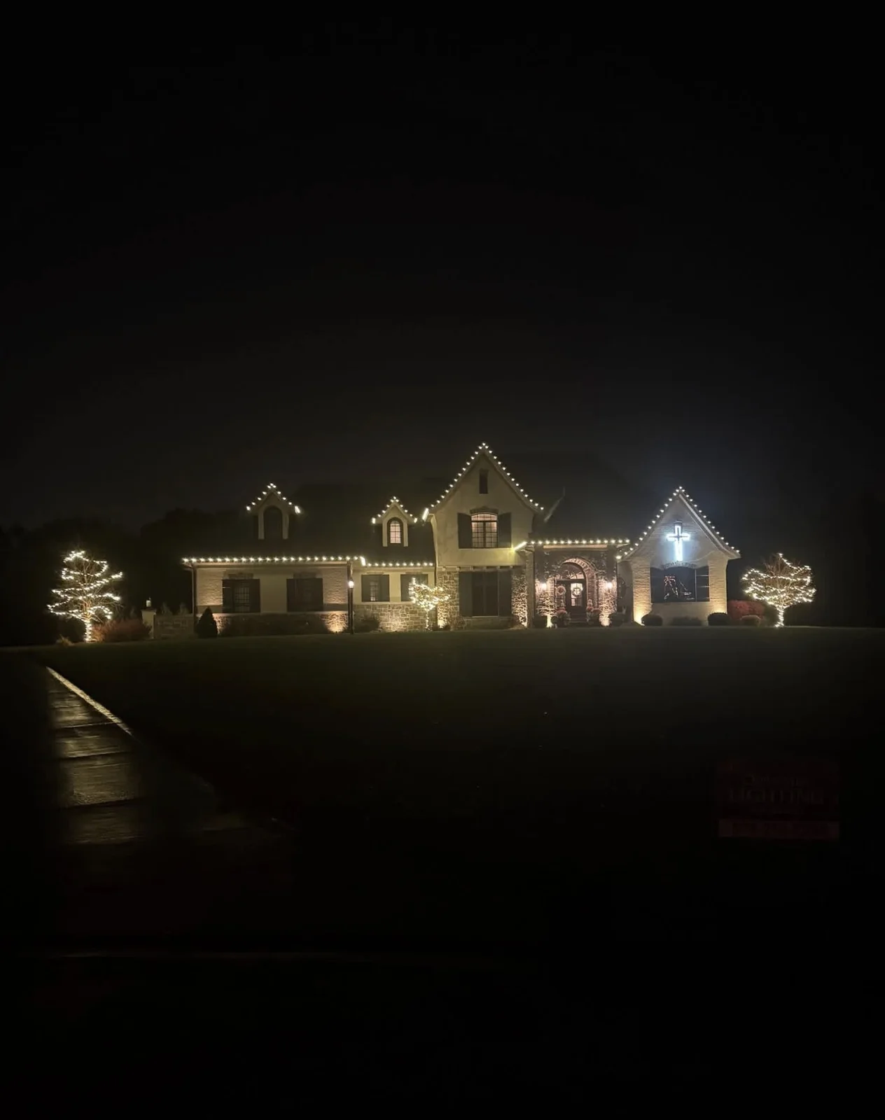 Wide residential exterior with warm-white holiday roofline lighting at night