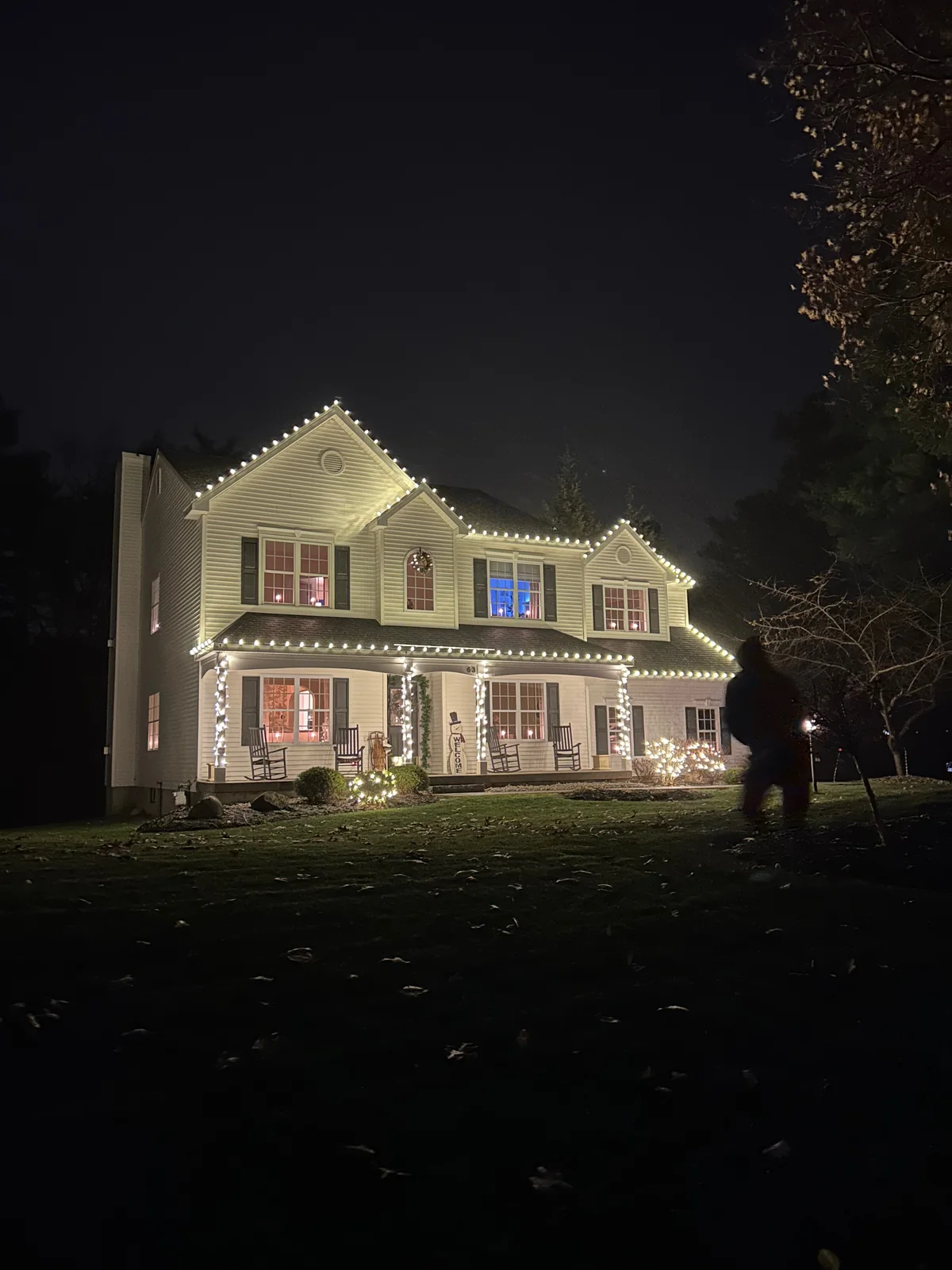 Custom warm-white roofline, porch, and landscape lighting on a multi-gable home